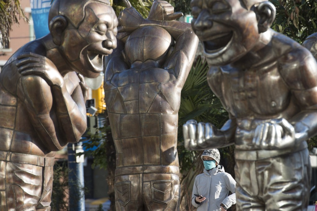 A woman wears a face mask as she walks past statues at English Bay in Vancouver, British Columbia, on Tuesday. Photo: AP