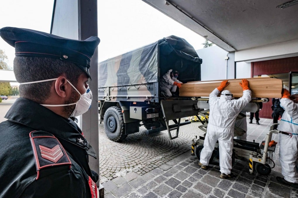 Italian soldiers wearing protective suits transport coffins onto military trucks from the Bergamo area to the a cemetery near Milan on Friday. Photo: EPA-EFE