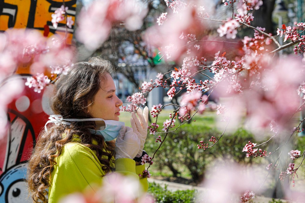 A girl removes her face mask to smell flowers amid a coronavirus outbreak in North Macedonia. Photo: Reuters