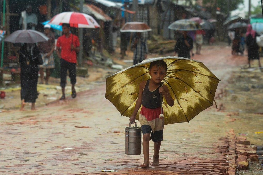 A young Rohingya refugee shelters under an umbrella as he makes his way amid monsoon rains at Kutupalong refugee camp in Bangladesh on September 12, 2019. Photo: AFP