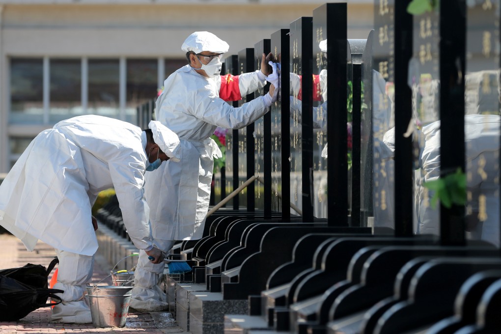 Staff wearing protective suits and face masks sweep tombs on behalf of families at the Babaoshan Cemetery in Beijing. Photo: Reuters