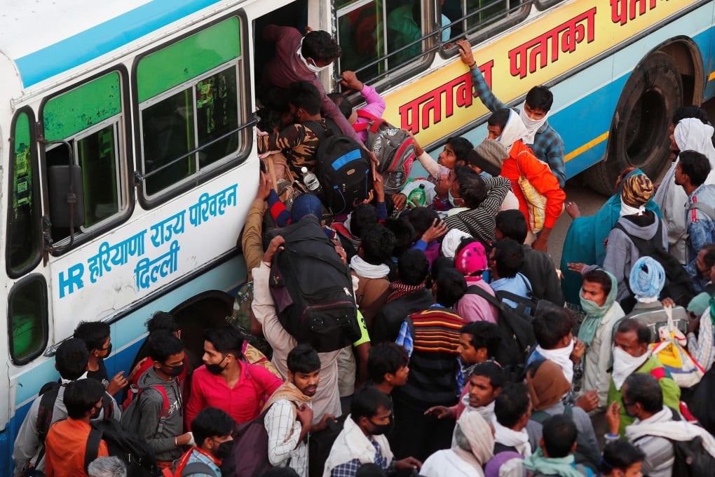 Migrant workers try to board a crowded bus as they return to their villages, during a 21-day nationwide lockdown to limit the spreading of Covid-19, in Ghaziabad, on the outskirts of New Delhi, India. Photo: Reuters