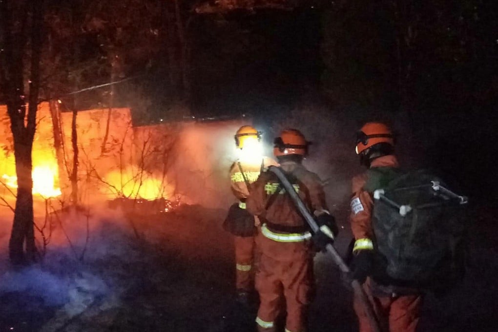 Firefighters work to put out the forest fire as it approaches a petrol station in Xichang, Sichuan province on Tuesday. Photo: EPA-EFE