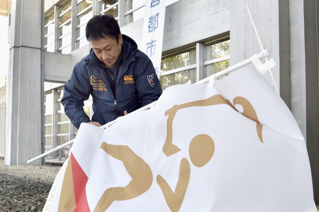 An official removes banners promoting the 2020 Tokyo Olympic torch relay at Inazawa City Hall in the Aichi prefectural city in central Japan. Photo: Kyodo