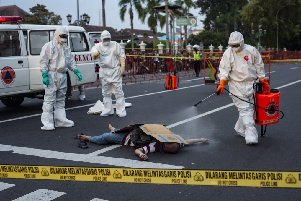 Paramedics wearing protective suits spray disinfectant on the body of a man who died suddenly on the street in Yogyakarta, Indonesia on Monday. Photo: EPA-EFE