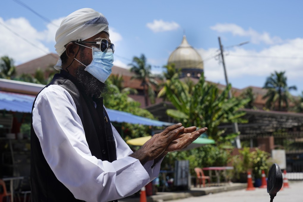 A Muslim man wearing a face mask uses hand sanitiser as he walks out from Sri Petaling Mosque in Kuala Lumpur, Malaysia on March 16. Photo: AP