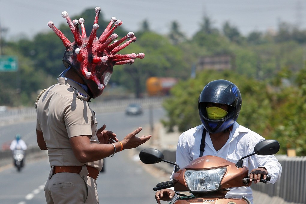 Police inspector Rajesh Babu, wearing a helmet depicting the coronavirus, asks a motorcycle rider to go home in Chennai, India, on Saturday. Photo: Reuters