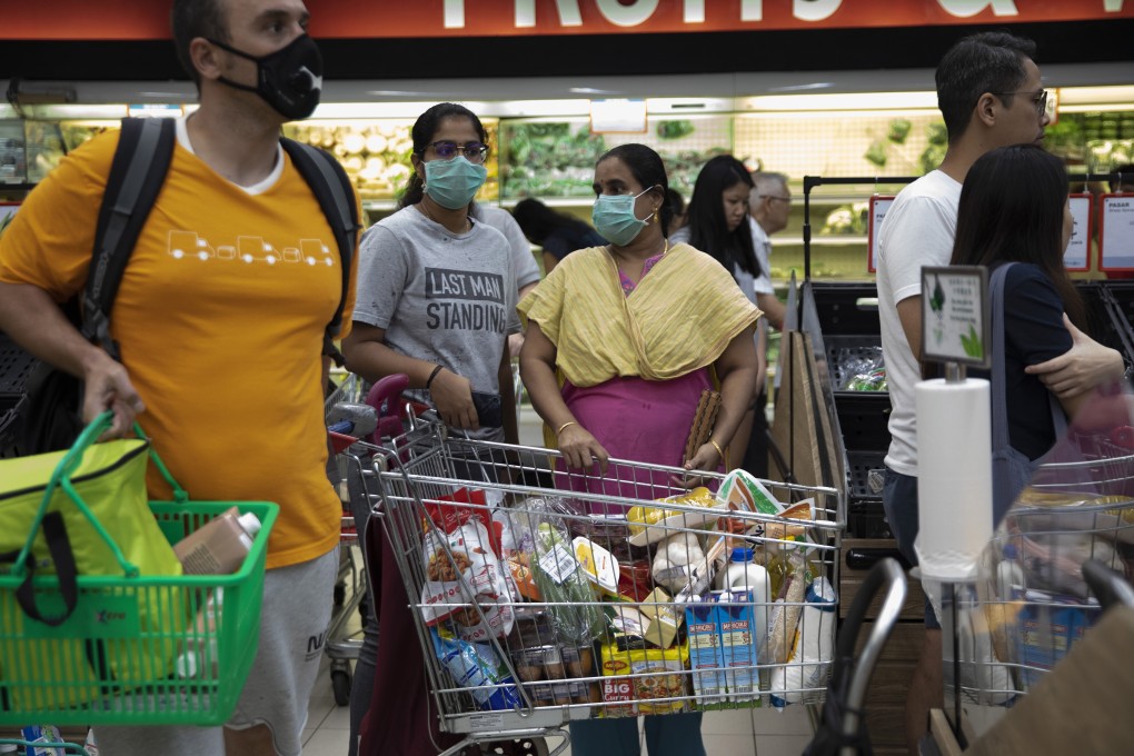 People queue to buy food and groceries at a branch of local supermarket chain NTUC Fairprice in Singapore on March 17. Photo: EPA-EFE
