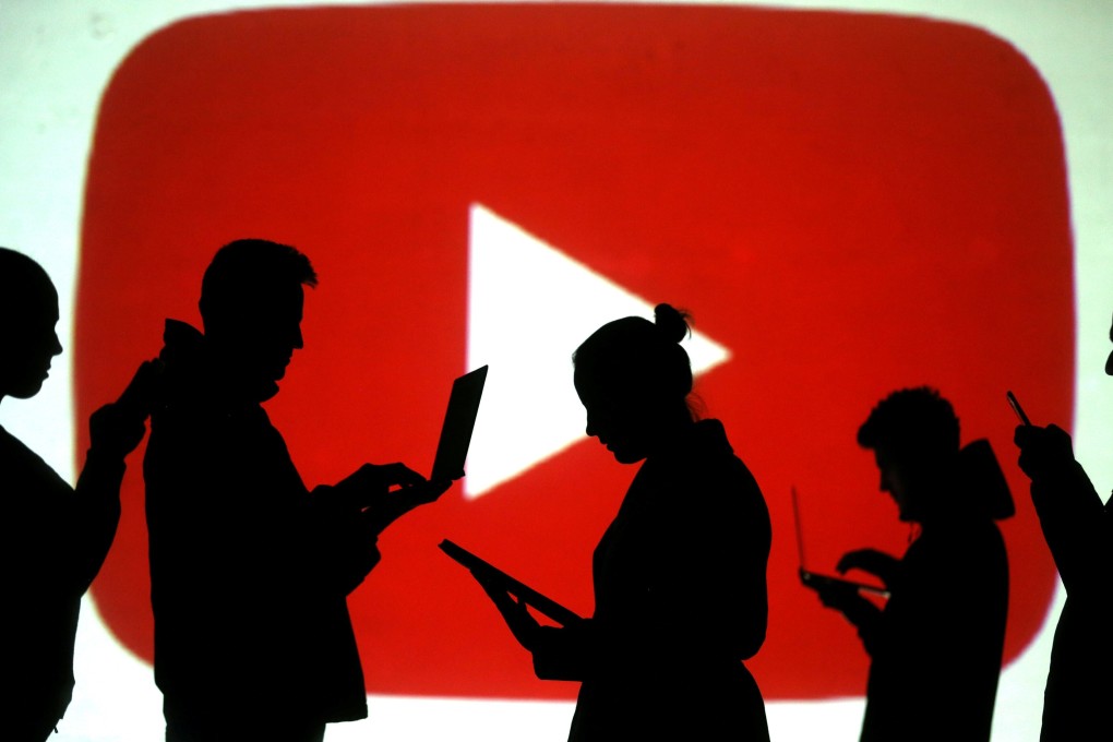 Silhouettes of laptop and mobile device users are seen next to a screen projection of YouTube’s logo in this picture illustration. Photo: Reuters/Dado Ruvic