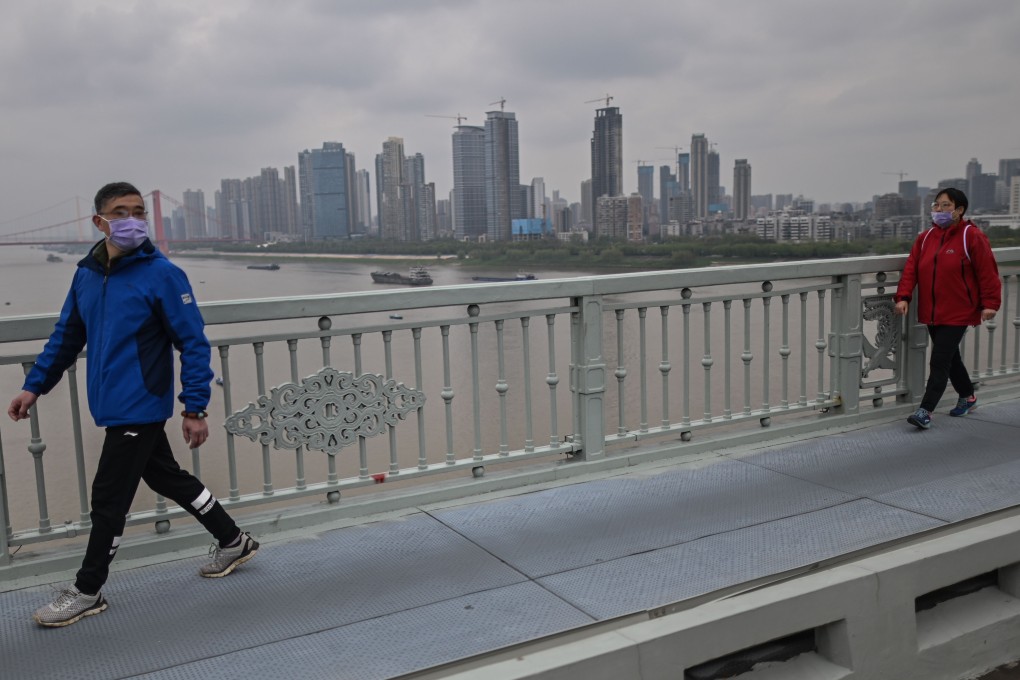 People wearing face masks cross a bridge in Wuhan, capital of central China's Hubei province on March 30, as travel restrictions into the city were eased after more than two months on lockdown to curb the spread of the coronavirus. Photo: Agence France-Presse