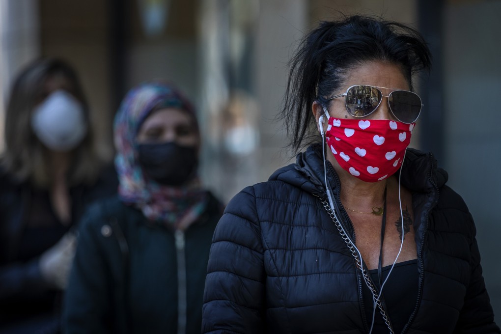 People wearing face masks line up to buy supplies from a shop in Spain on April 4, 2020. Photo: AP