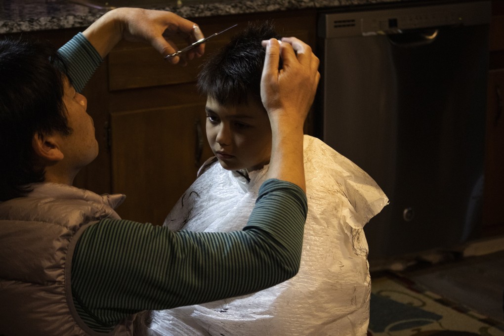 Naoto Ikeda cuts his son Noah’s hair in the kitchen of their home. Photo: AP