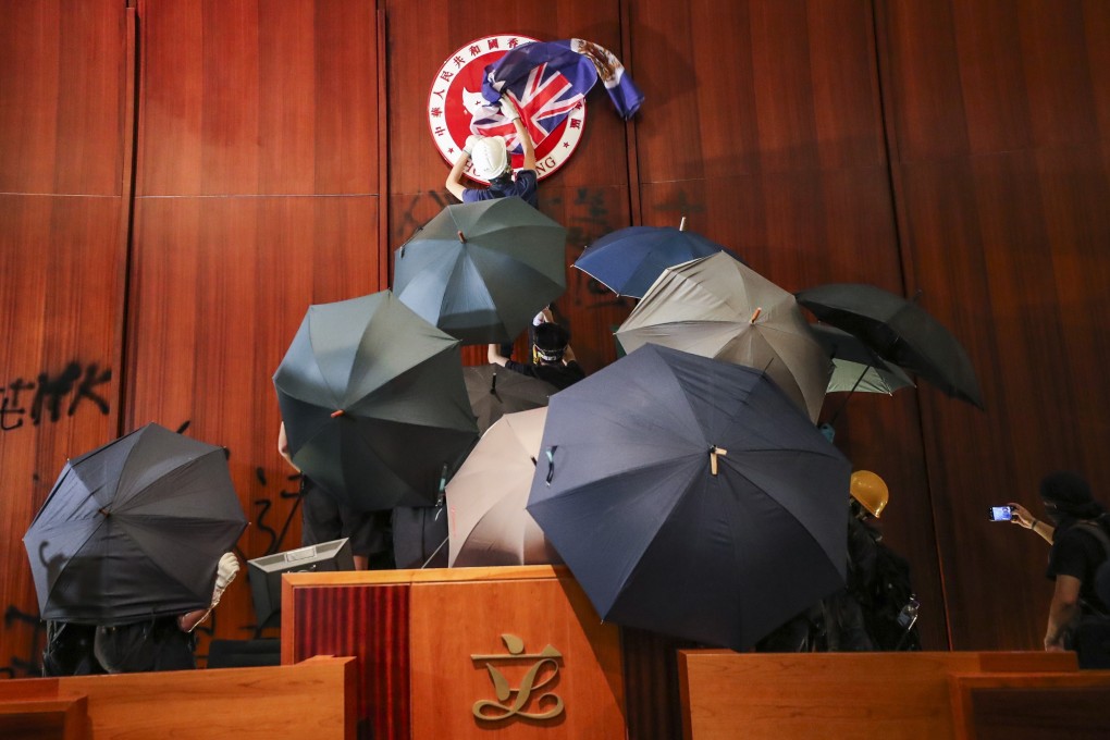A protester covers the emblem of Hong Kong with a British colonial flag during a storming of the Legislative Council in Tamar on July 1 last year. Photo: Sam Tsang