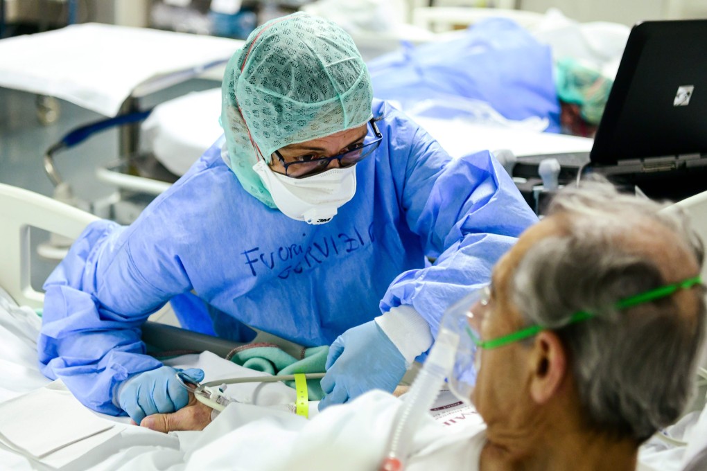 A member of the medical staff comforts a patient infected by the coronavirus at a hospital in Bergamo, Italy. Photo: AFP