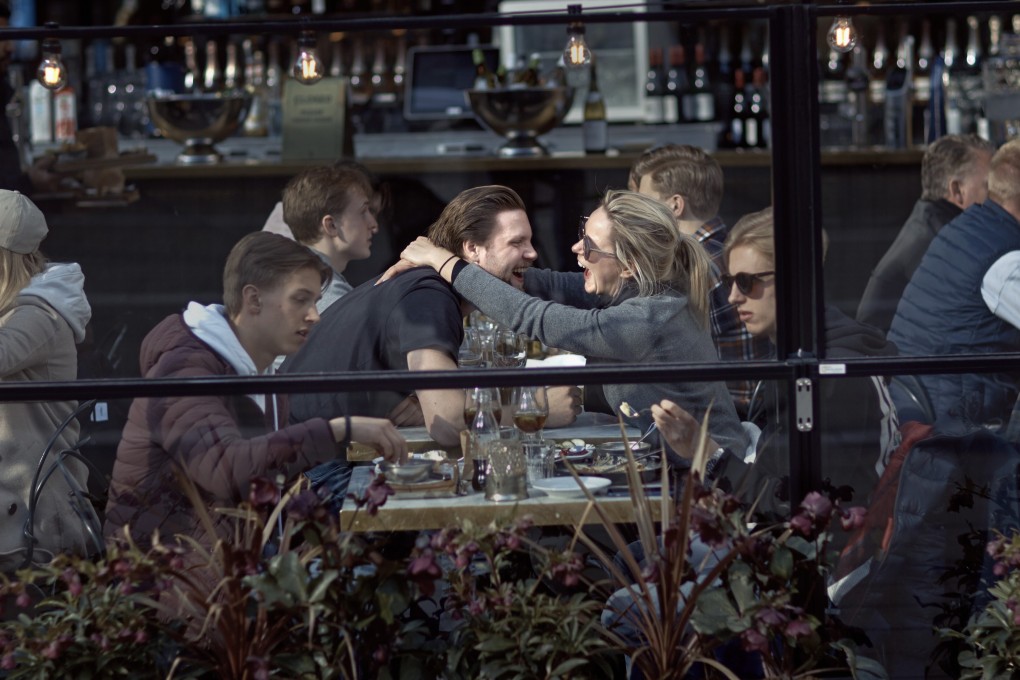 A couple hug and laugh as they have lunch in a restaurant in Stockholm, Sweden, on Saturday. Swedish authorities have advised the public to practice social distancing. Photo: AP