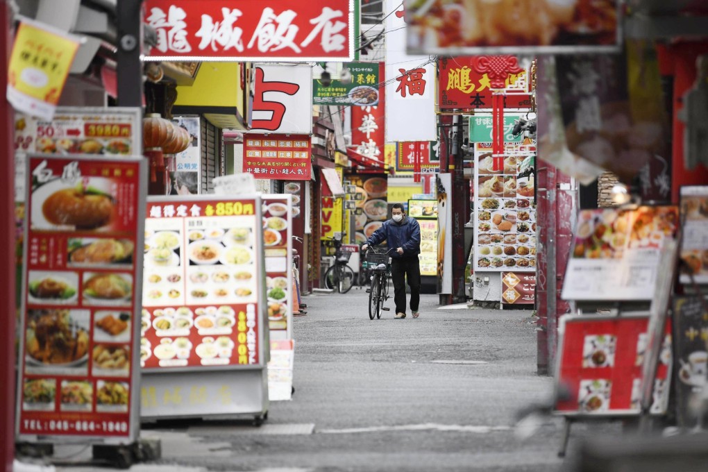 A man walks a bicycle through an almost empty street in Yokohama, near Tokyo, on Sunday afternoon. Photo: Kyodo
