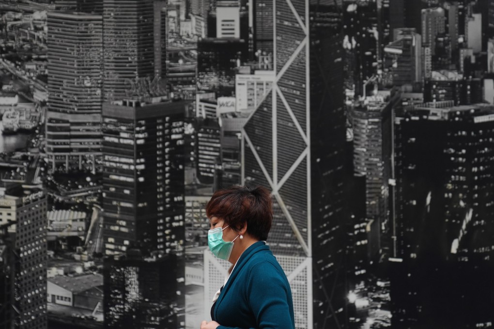 A woman wears a mask while walking in North Point with an image of the Hong Kong skyline behind her. Photo: Sam Tsang