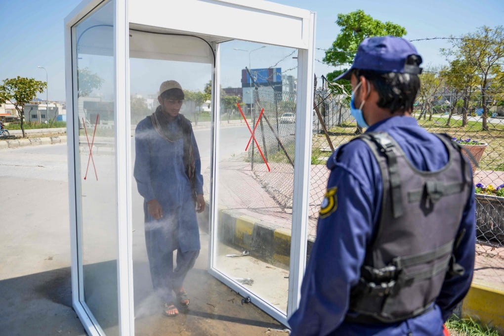 A man walks through a disinfecting booth on a street in Rawalpindi, Pakistan. Photo: AFP