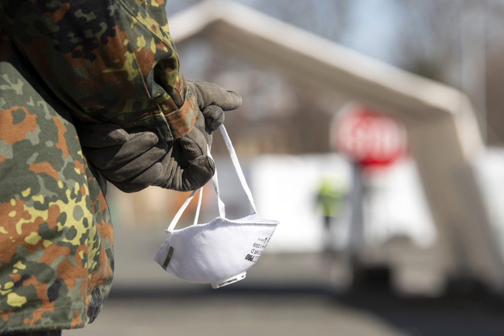 A member of the German armed forces holds a face mask in Gera, Germany. Photo: AP