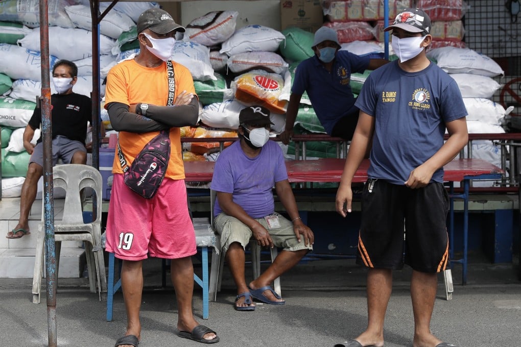 Men wearing protective masks stand near a village hall during the coronavirus lockdown in Manila on Friday. Photo: AP
