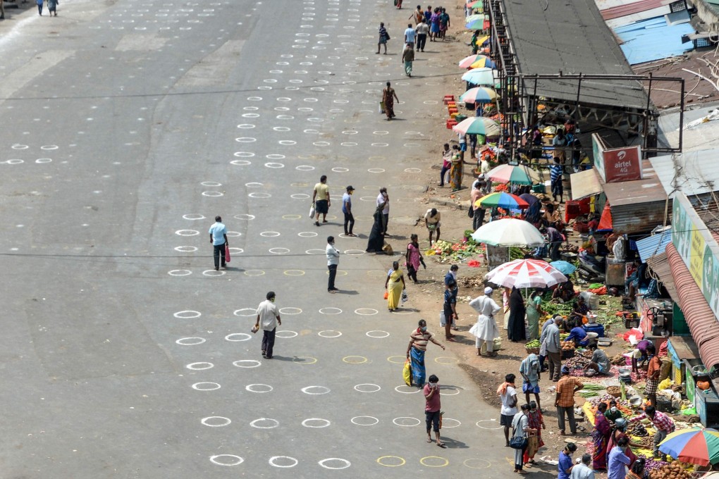 People walk in an area with circles marked on the floor for social distancing as they buy groceries at a temporary market in Chennai, India. Photo: AFP