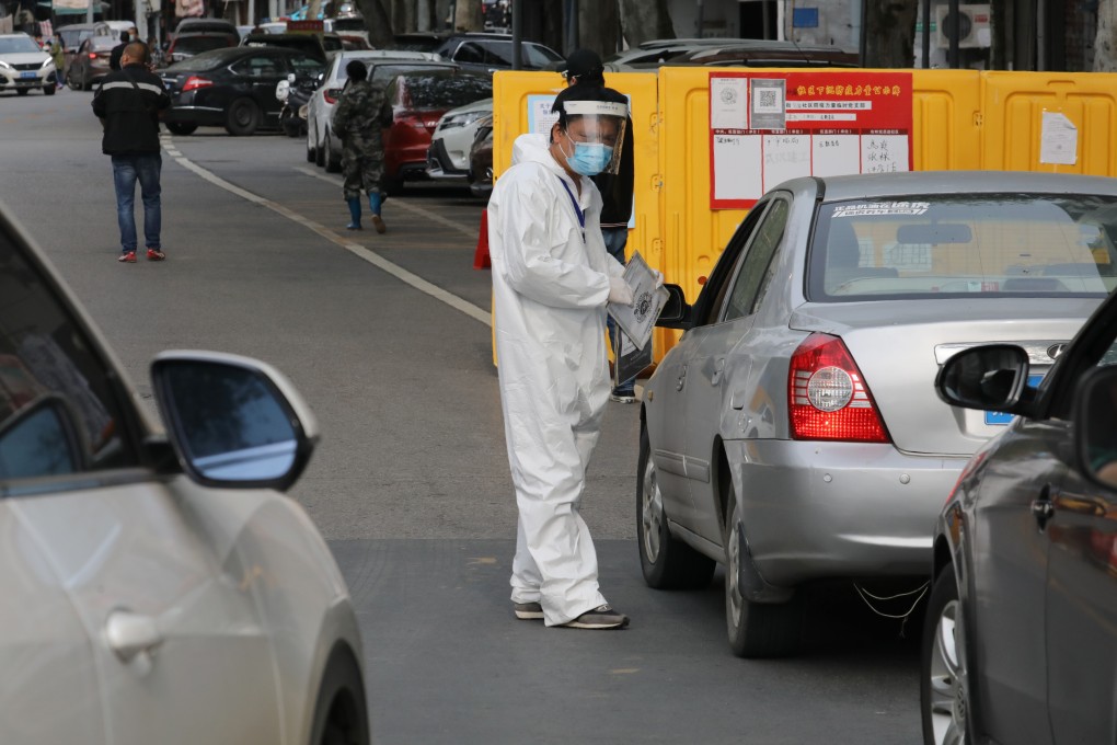 A fully covered man requires car drivers to scan the QR code to enter a community in Wuchang district, in Wuhan city, central China's Hubei province. Photo: Simon Song