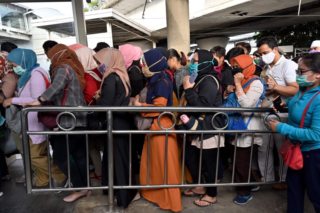 Commuters wearing face masks queue at a railway station in Jakarta on Monday. Photo: AFP