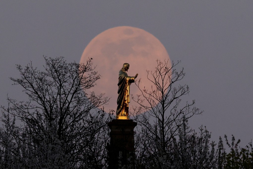 The pink supermoon rises behind the Sacre-Coeur du Horn statue near Strasbourg, France on Tuesday. Photo: Reuters
