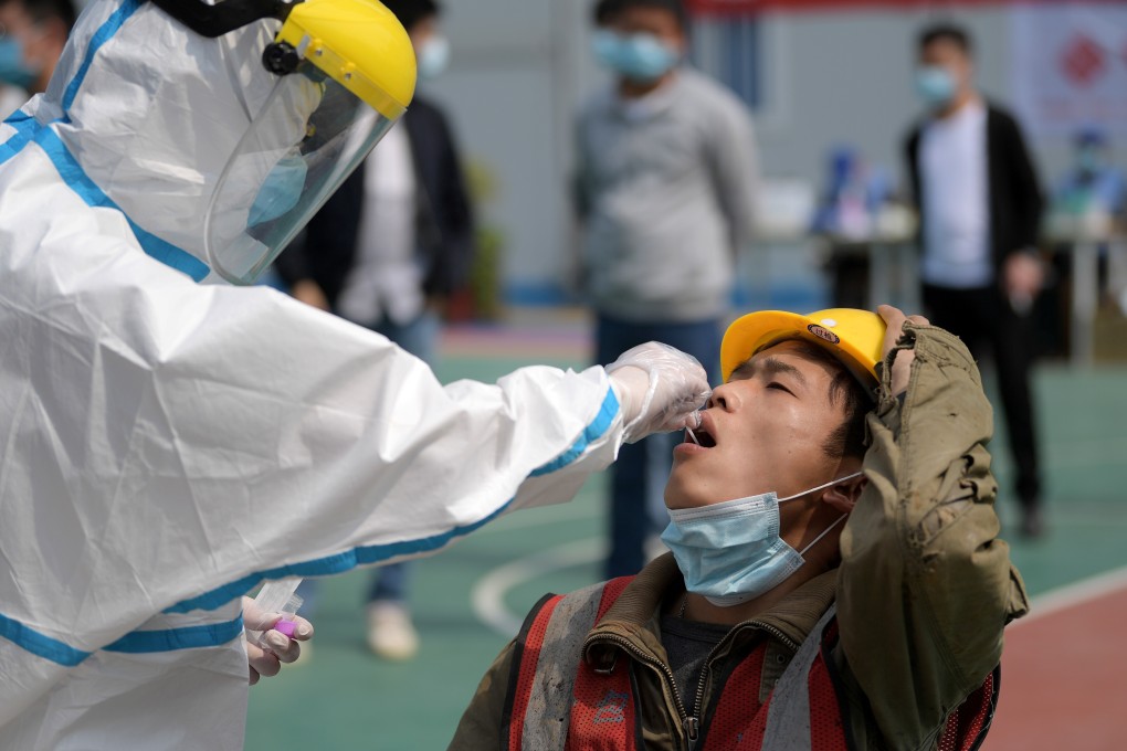 A worker in a protective suit collects a swab from a construction worker for nucleic acid test in Wuhan, Hubei province, in China on April 7. Photo: Reuters