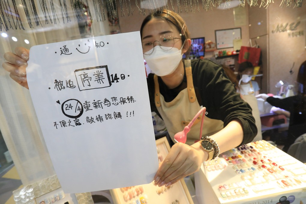 Tang Tze-ching puts up a sign saying the nail salon she works at in New Town Mall, Mong Kok, will be closed for 14 days because of government rules designed to slow the spread of the coronavirus. Photo: May Tse