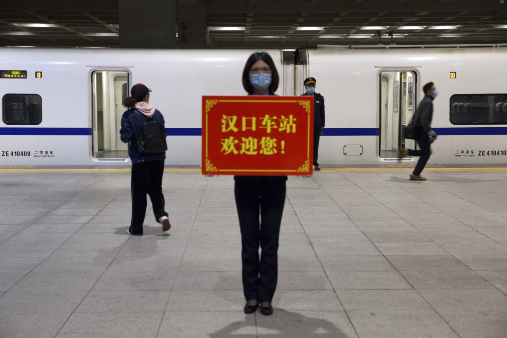 A railway worker holds a sign reading “Hankou Station welcomes you!” as passengers board the first high-speed train to leave after the resumption of services in Wuhan, Hubei, on April 8, after 11 weeks of lockdown. Photo: AP
