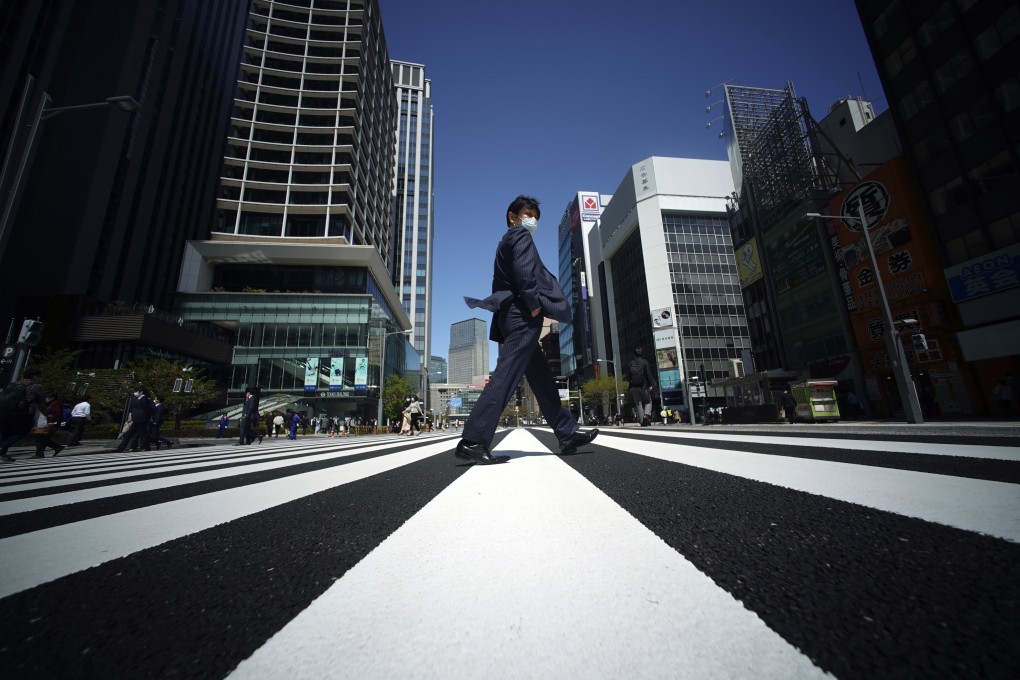 A man wearing a protective mask to help curb the spread of the coronavirus crosses a pedestrian walkway in Tokyo on April 10. Photo: AP