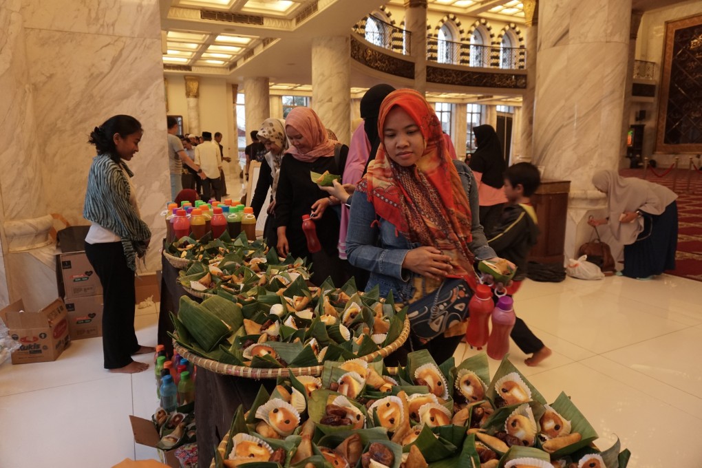 Greenpeace staff help distribute food wrapped in banana leaves and drinks in reusable bottles at a mosque during Iftar. Photo: Greenpeace