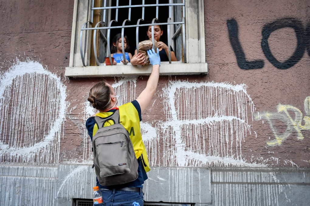A volunteer distributes basic necessities to people during a lockdown in Milan, Italy. Photo: DPA