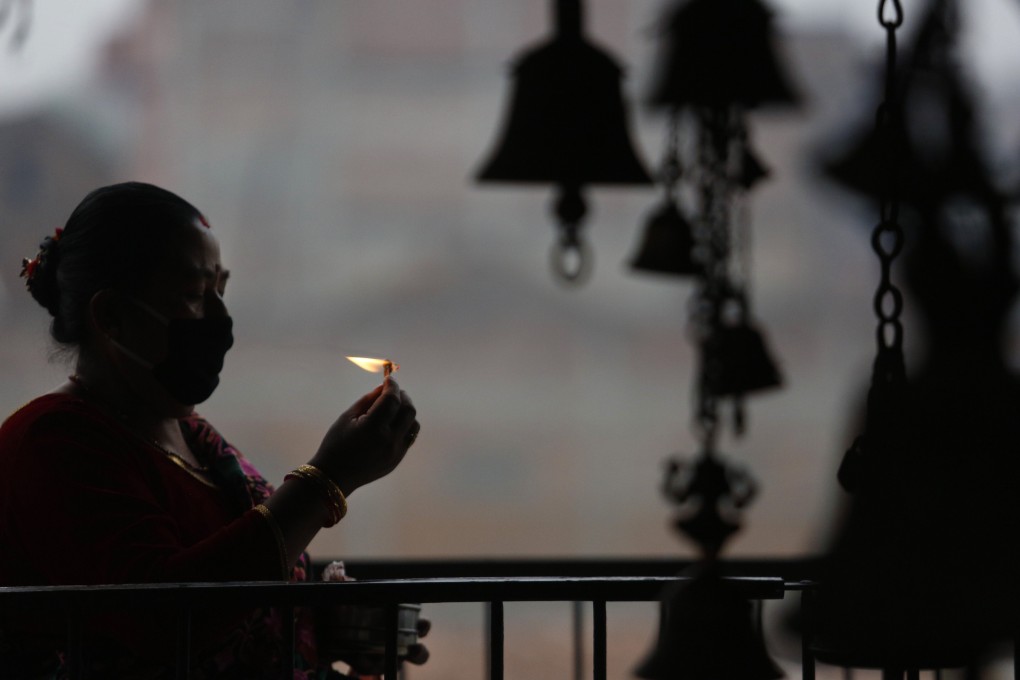 A woman wearing a face mask burns an oil lamp marking Biska Jatra festival, during a lockdown to prevent the spread of the new coronavirus in Bhaktapur, Nepal, on April 13. Photo: AP