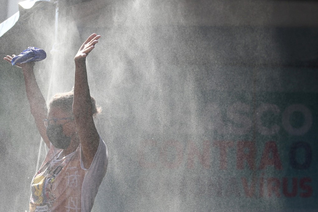 A woman passes by a spray of disinfectant solution at a railway station entrance in Osasco, Sao Paulo State, Brazil on Monday. Photo: Reuters