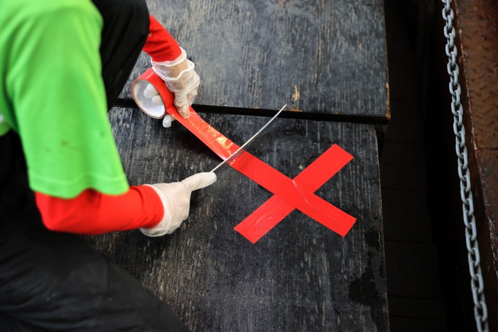 An employee marks spots to remind customers to maintain social distancing at Captain Whites Seafood City in the reopened Municipal Fish Market in Washington on Monday. Photo: AFP