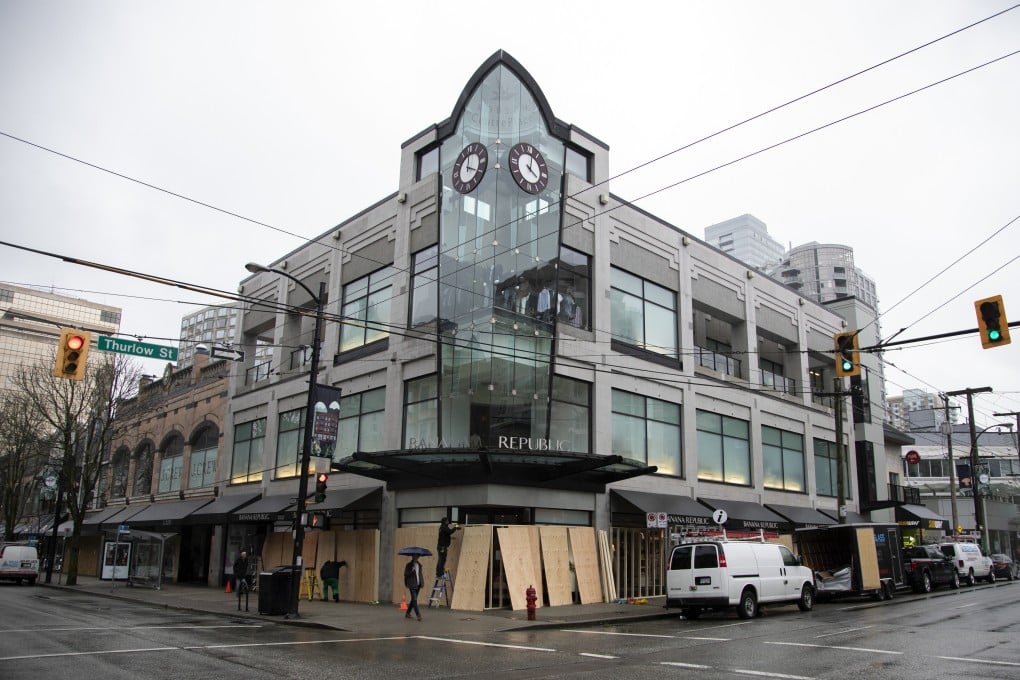 Workers board up shops on Robson Street in Vancouver, British Columbia, on March 27. Photo: Bloomberg