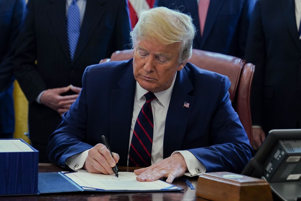 US President Donald Trump signs the coronavirus stimulus relief package in the Oval Office in March. Photo: AP