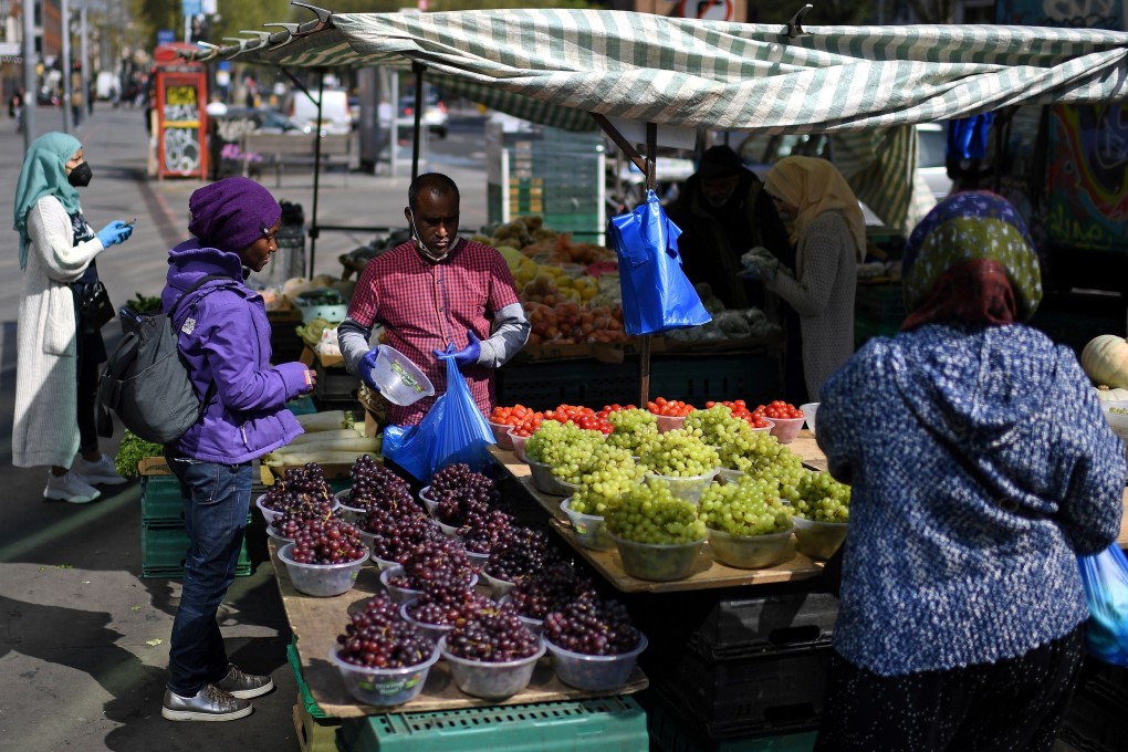 Customers buy fruit and vegetables from a stall at Whitechapel market in east London. Photo: AFP