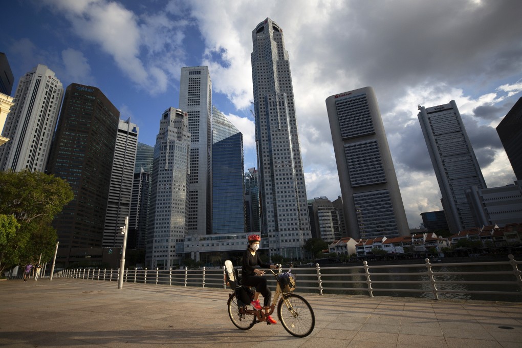 A cyclist wearing a face mask rides in front of the Central Business District in Singapore. Photo: EPA