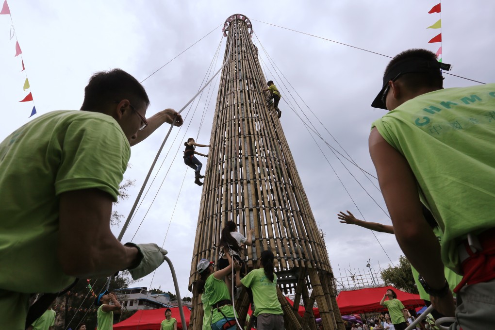 Participants try to climb a bun tower outside Cheung Chau Pak Tai Temple Playground during the 2015 Bun Carnival in Hong Kong. Photo: Jonathan Wong
