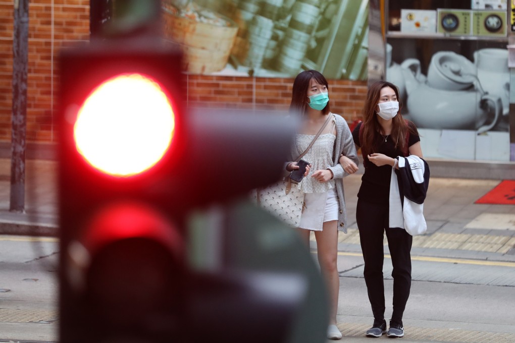 Two women wearing masks wait to cross the street in Hong Kong on April 11 as the city fights to contain the coronavirus outbreak. At the end of April, Hong Kong will have been fighting Covid-19 for three months. Photo: Xinhua