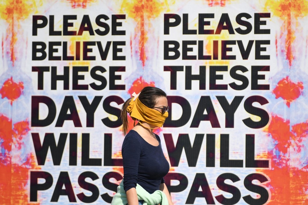 A woman wearing mask walks past a mural attributed to English artist Mark Tichner and displayed on billboards, in London on April 9. Photo: EPA-EFE