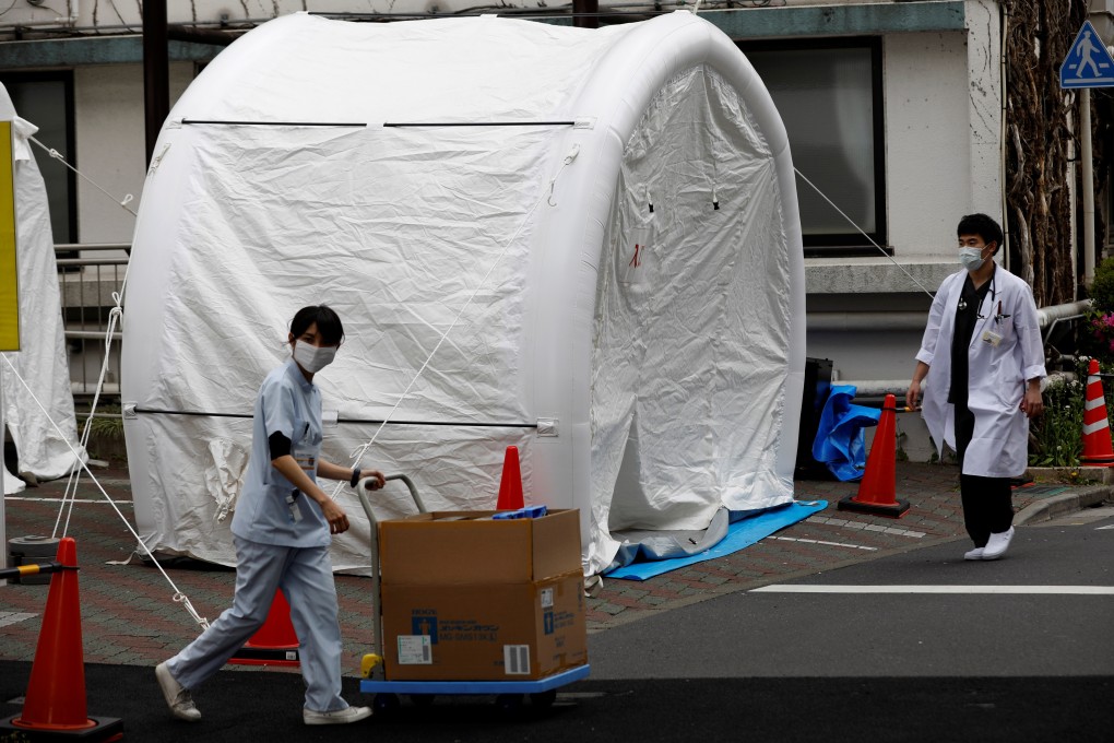 Japanese medical workers walk past tents set up to test for coronavirus. Photo: Reuters