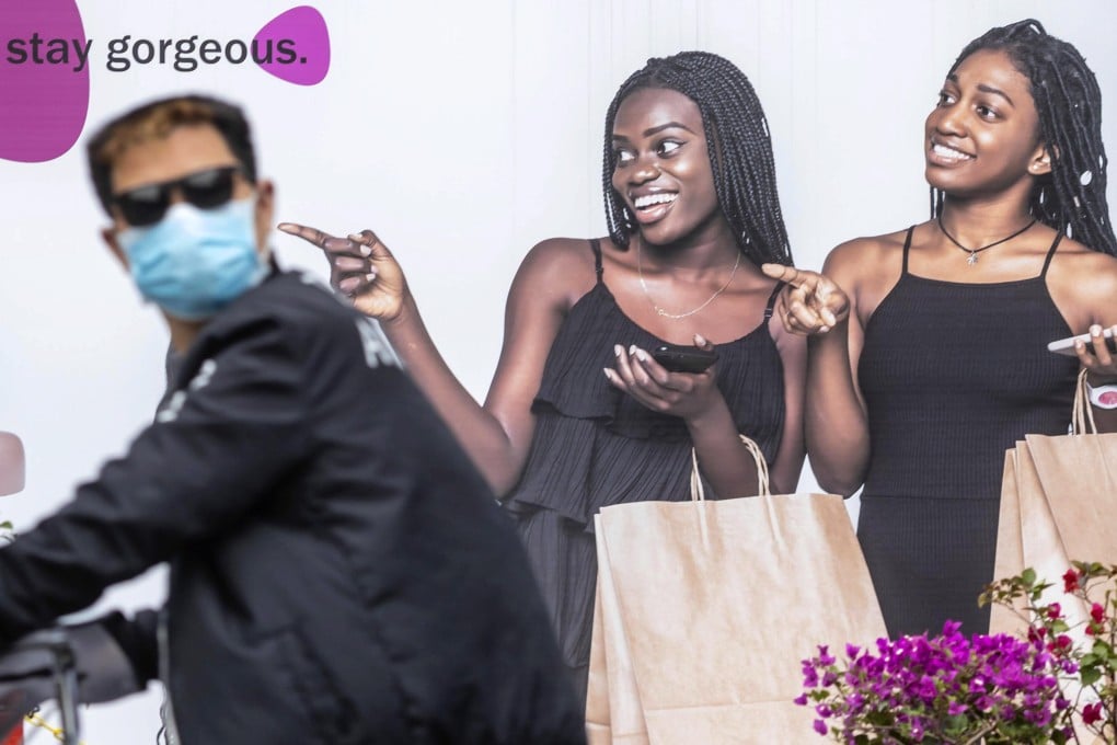 A cyclist passes a poster in a part of Guangzhou where most African people live and work. Photo: EPA-EFE