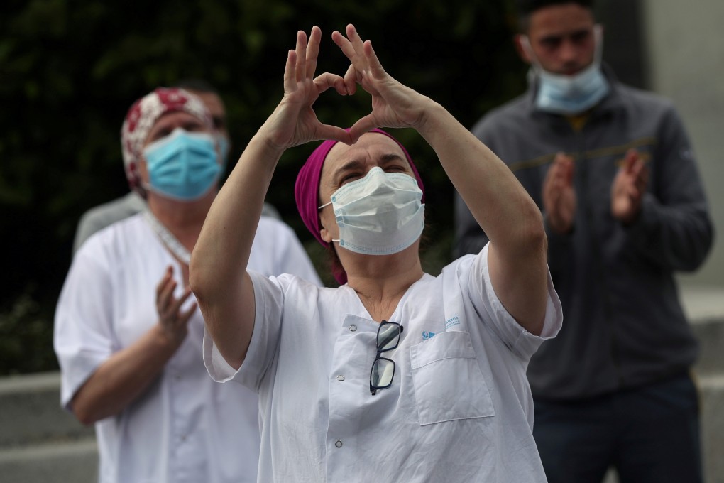 Staff from La Paz hospital in Madrid, Spain, gesture towards colleagues after taking a minute of silence to remember the hospital's chief of surgery who died of Covid-19. Photo: Reuters