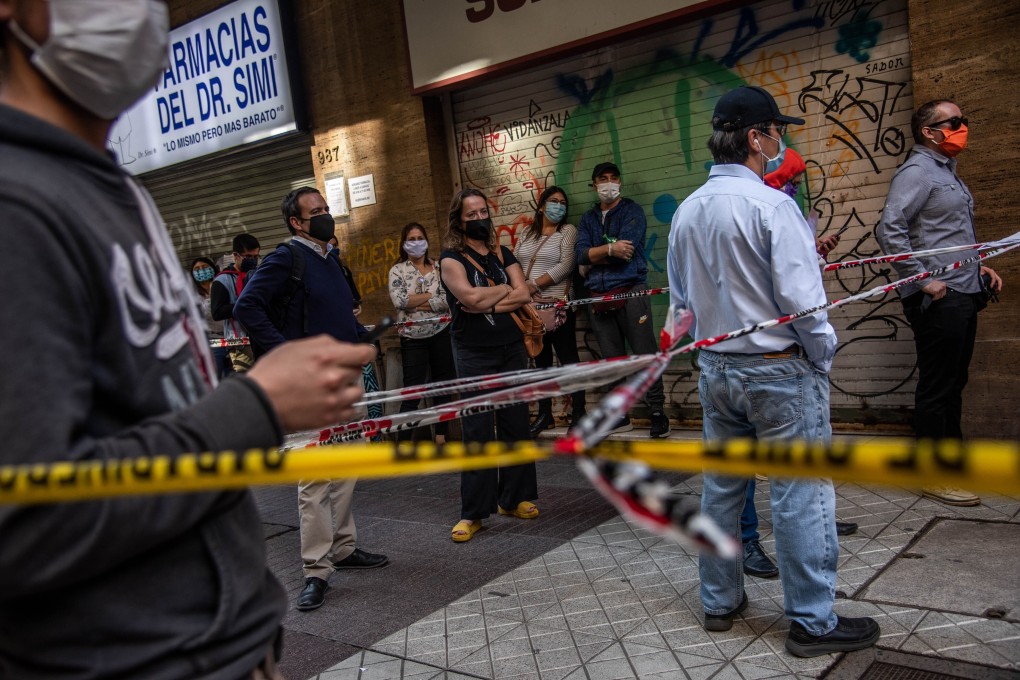 People wearing protective masks wait in line to present documents at a notary office in Santiago, Chile. Photo: Bloomberg