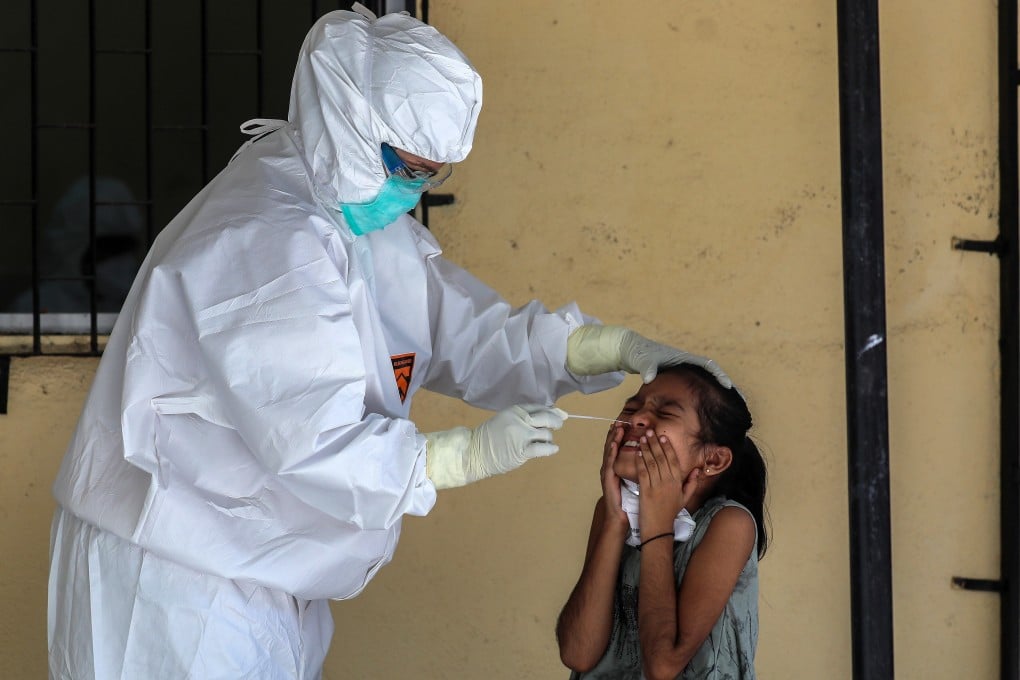 A member of medical staff in protective gear collects a swab sample from a girl in India’s Mumbai earlier this month. Photo: EPA