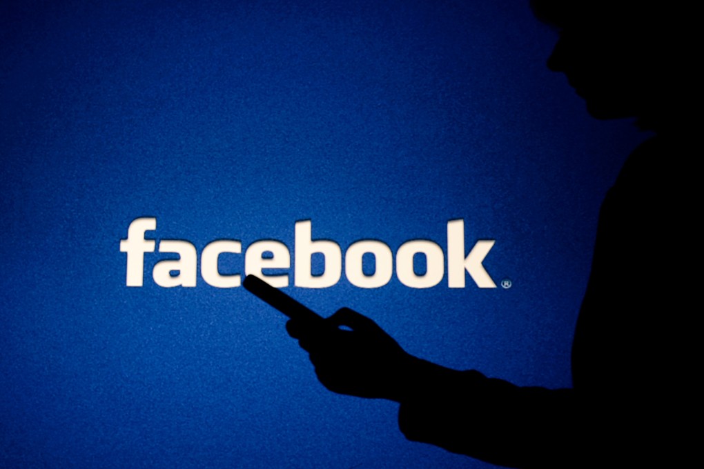 A woman looks into the smartphone in front of Facebook logo. Photo: Shutterstock